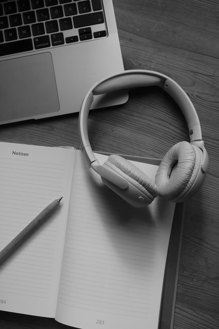 Podcast Managerin sitzt auf einem Sofa mit Notizheft und Stift in der Hand