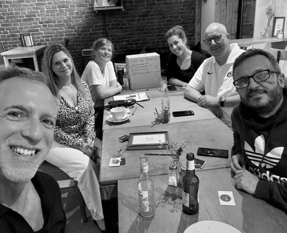 Stammtisch_Juni Eine Gruppe Menschen sitzt um einen Tisch mit Getränken